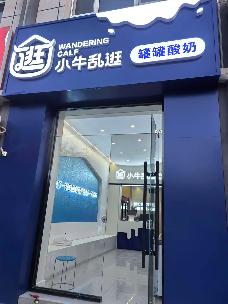 小牛乱逛门店门头实拍：品牌中英文组合「小牛乱逛 WANDERING CALF」与「罐罐酸奶」品类标识，下方柜眉标语「为了一杯好酸奶　我们经营了一个牧场」