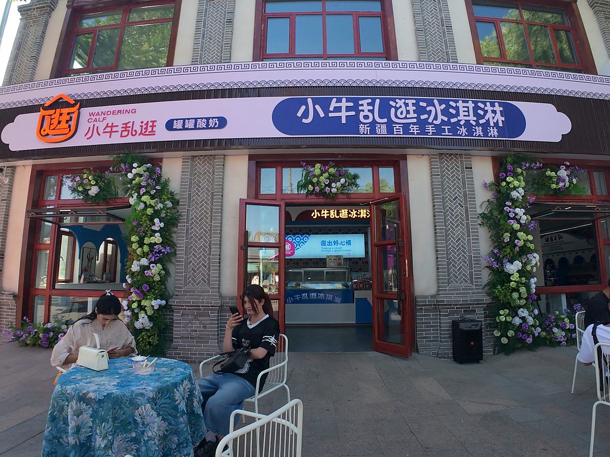 小牛乱逛街边门店实拍：门头上并置「新疆百年手工冰淇淋」与「小牛乱逛　罐罐酸奶」双招牌，下方为「逛出好心情」标语