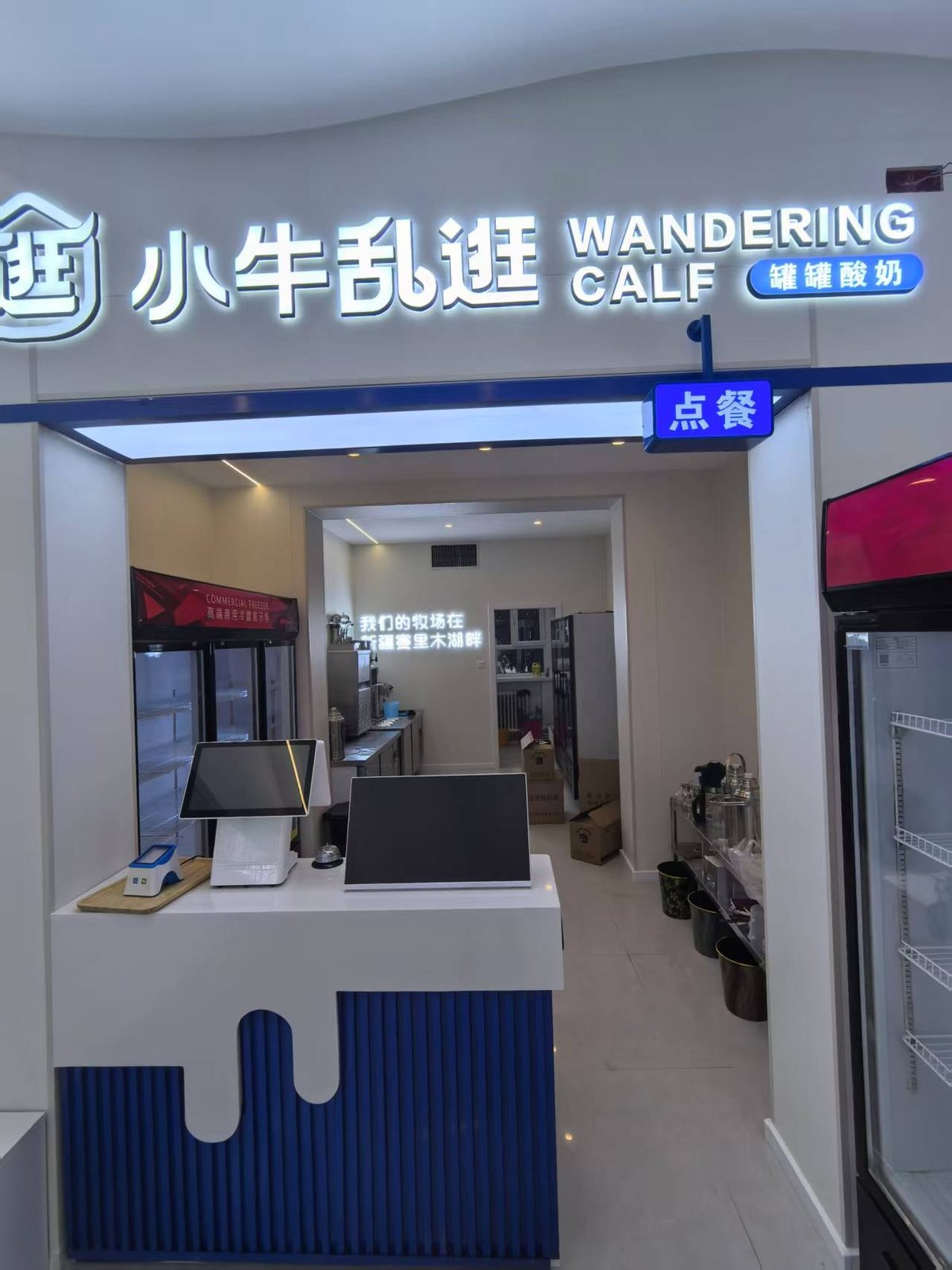 店里的白吧台与“点餐”牌；后墙上写着“我们的牧场在，新疆赛里木湖畔”。