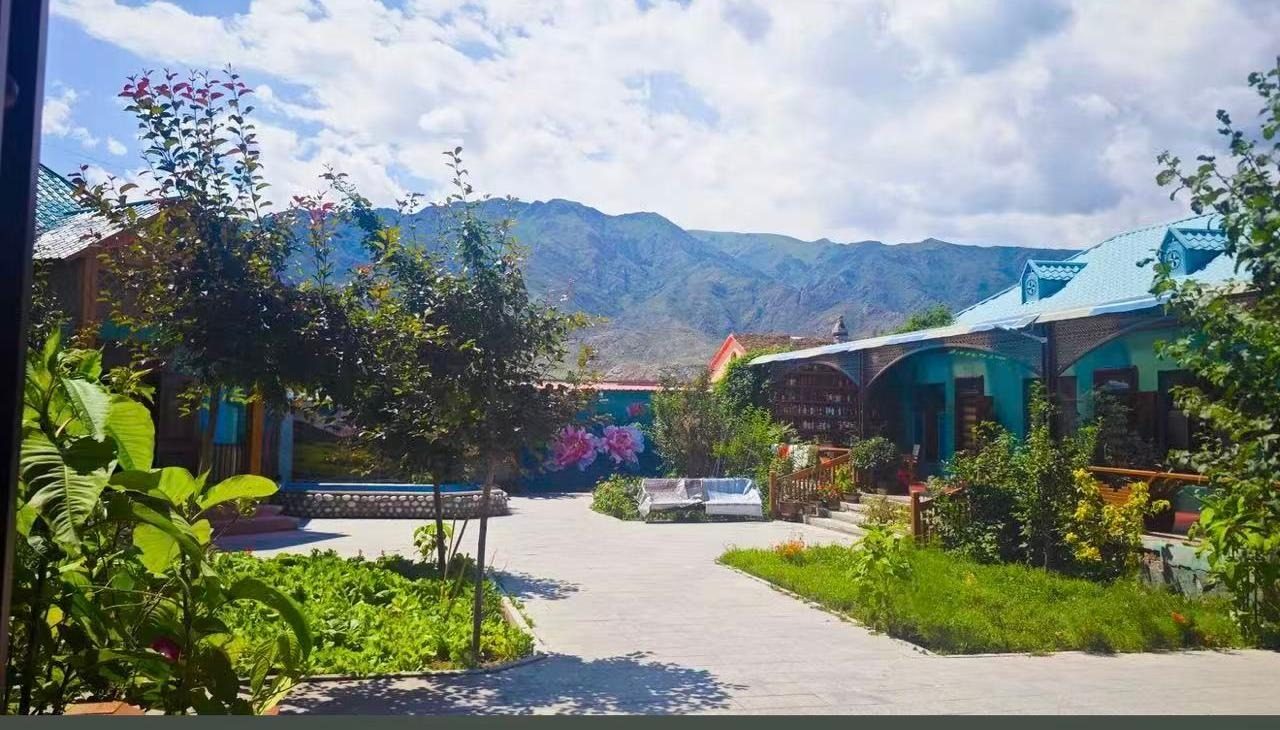 绿多多的院子：花砖墙、菜地、两排青绿屋顶的平房，抬头是山。（稳妥封面）