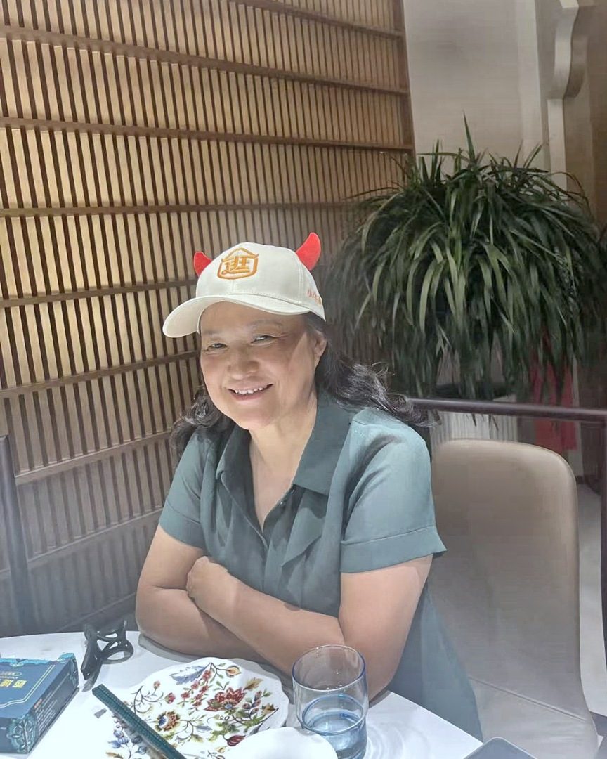 她戴着自家的帽子，坐在饭桌边。