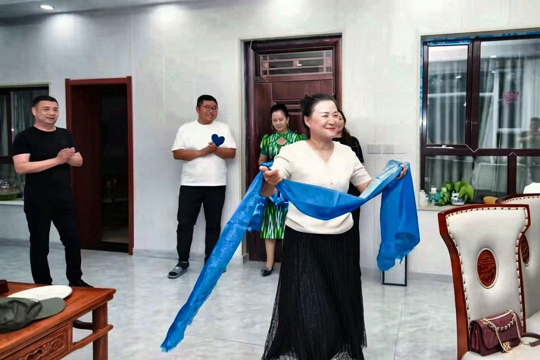 迎宾时，她手捧一条蓝绸。