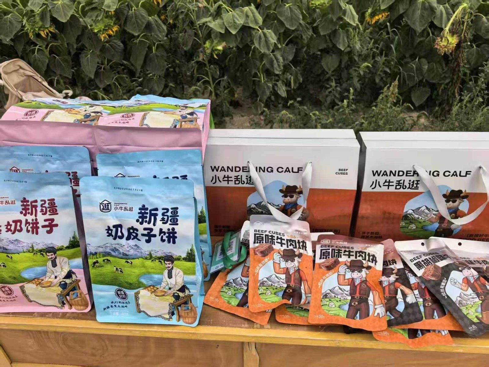 户外的木桌上摆着奶皮子饼与牛肉块，身后是向日葵田。