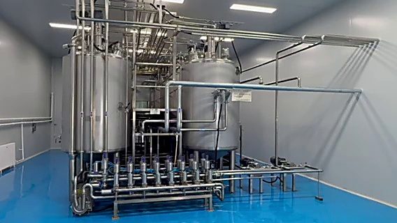 发酵罐车间全景。一排不锈钢立式罐，接管密布，横管沿墙走线。